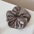 Detail of a dark brown French style fabric scrunchie with a white Hand Made woven label - Scrunchie / Camel