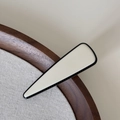 Détail d'une pince à cheveux crème minimaliste avec bord noir sur fond en lin - Pince Blanche Triangle