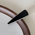Détail macro d'une pince à cheveux triangulaire noire avec bordure argentée sur bois - Pince Noire Triangle