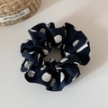 Primo piano di un elastico per capelli a pois bianchi e neri con etichetta in tessuto - Nero