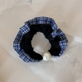 Detail view of plaid lace hair scrunchie with a large pearl on white wrinkled paper - Blue