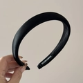 Detail view of the black satin padded headband featuring a woven handmade textile label - Black