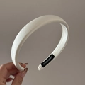 Detailed close-up of a white satin padded headband with a black handmade label tag - White