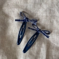 Détail de deux barrettes à cheveux à nœud vichy bleu et blanc sur fond de lin rustique - Paire Barrettes Nœud Plaid Bleu