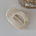 Détail macro d'une pince à cheveux ovale en acétate crème marbré avec petit logo doré chic - Style Marbre Ovale (FJ892543) / Blanc Cassé