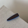 Détail d'une pince à cheveux en résine bleue avec centre en tissu marron sur fond beige - Triangulaire / Café