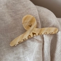 Détail d'une pince à cheveux en acétate marbré crème sur un tissu en lin beige doux - Motif Marbre Blanc Cassé