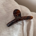 Détail d'une pince à cheveux écaille de tortue avec lettrage doré sur tissu beige - Écaille Café Foncé