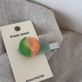Macro shot of a realistic tangerine fruit design hair clip on a display card - Orange