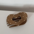 Detailed view of the brown polka dot heart shaped acrylic hair clip flat on the desk - Heart Coffee
