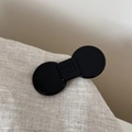 Detail shot of black acetate bow hair clip with engraved lettering on smooth surface - Medium Bowknot Style / Black