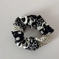 Close-up of black and white polka dot pleated fabric scrunchie with elastic band texture - Black and White Patchwork