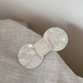 Macro detail of white acetate bow hair clip with embossed lettering on linen fabric - Large Bow Style / White