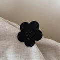 Détail macro d'une pince à cheveux fleur en acétate noir brillant avec lettrage - Style Floral Moyen / Noir