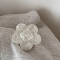 Macro detail of white acetate flower hair clip featuring engraved wer letter logo - Large Flower Style / White