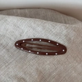 Detailed view of an oval brown hair clip with white polka dots on a textured fabric - Polka Dot Oval-Coffee