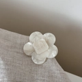 Detailed close-up of cream white acetate flower hair clip with pearl luster and engraving - Medium Floral Style / White