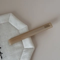 Detail van handgemaakte acetaat haarklem in beige houtnerfpatroon met Franse opdruk - Lange Stijl / Beige Abrikoos