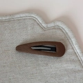 Gros plan sur des barrettes BB marron en forme de goutte avec texture mate sur lin - Café Goutte d'Eau