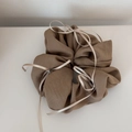 Détail d'un chouchou en tissu côtelé marron orné d'élégants nœuds en ruban blanc - Abricot