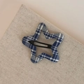 Dettaglio ravvicinato di un fermaglio a stella con trama in tessuto a quadretti bianchi e blu - Plaid Blu BB-Stella a Cinque Punte