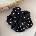 Detailaufnahme des schwarzen Satin-Haargummis mit weißen Punkten und weichen Falten - Scrunchie / Schwarz