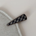 Dettaglio macro di un fermaglio per capelli triangolare in tessuto scozzese blu e resina - Fermaglio Triangolo A Quadri Britannico / Nero