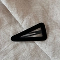 Close-up of a black triangular velvet hair clip on a minimalist beige linen background - Triangle / Black