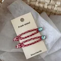 Dettaglio di fermagli per capelli a quadretti rossi con strass blu su cartoncino - Rosso