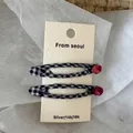 Dettagli di due fermagli per capelli a quadretti bianchi e neri con strass rosa su una card - Nero