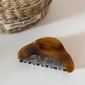 Macro detail of amber resin shark hair claw clip with Barrette La France text engraving - Coffee