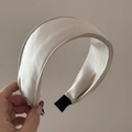 Nahaufnahme von gepolstertem Satin-Haarreifen mit glänzendem Stoff und Endkappen - Beige