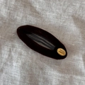 Détail de la pince à cheveux ovale en velours avec plaque dorée sur fond en lin - Marron