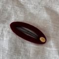 Détail d'une barrette à cheveux en velours bordeaux avec plaque dorée et texte SMILE HAPPY - Rouge