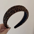 Detailopname van de zachte luipaard fluwelen textuur en het brede gewatteerde ontwerp van de haarband - Donker Luipaardprint Hobbelige Stijl
