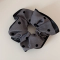 Detailed view of grey polka dot hair scrunchie with ruffled edges and black brand label - Gray Polka Dot