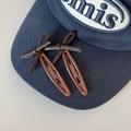 Detalle de pinzas para el cabello con lazo de cuero marrón en una gorra azul marino - Marrón