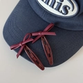 Primer plano detallado de pinzas para el cabello con lazo de cuero rojo en una gorra - Rojo