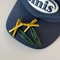 Primer plano de pinzas para el pelo verdes con lazos de cuero PU amarillo en gorra - Verde