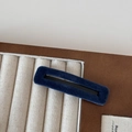 Detail view of rectangular velvet snap hair clip in navy blue finish on a display stand - Blue