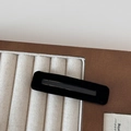Detail view of a black velvet rectangular BB hair clip on a beige linen jewelry display tray - Black