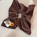 Détail d'un chouchou à carreaux marron avec bouton jaune et étiquette de chien - Élastique Carré à Carreaux Bouton Rouge Jaune