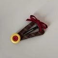 Détail d'une pince à cheveux à carreaux marron avec nœud rouge et bouton jaune vif - Pince BB Triangle à Carreaux Bouton Rouge Jaune