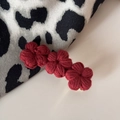 Dettaglio di tre fiori all'uncinetto rossi fatti a mano su una forcina con trama in filato - Rosso