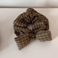 Détail d'un chouchou à nœud à carreaux vintage aux tons terreux sur fond blanc - Style Nœud / Plaid Jaune Café