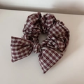 Détail d'un chouchou à nœud vichy rouge avec élastique durable et texture de tissu de qualité - Style Nœud / Carreaux Rouges