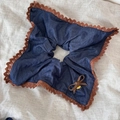 Détail d'un chouchou en denim bleu avec bordure en dentelle marron et pendentif doré - Chouchou Carré