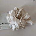 Detailed view of large cream-white satin scrunchie with soft glossy texture and folds - Off-white