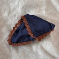 Détail d'un chouchou en tissu bleu denim avec bordure en dentelle café sur fond de lin - Pince à cheveux