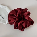 Detailed view of glossy burgundy satin scrunchie with rich silk textures and soft pleats - Red